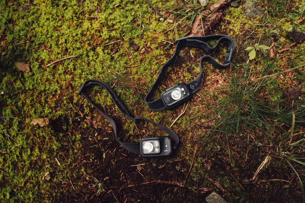 Two headlamps resting on moss and pine needles before a mountain elopement hike
