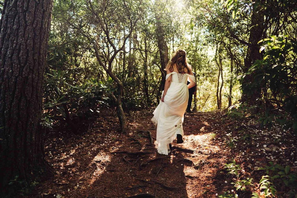 Kaitlyn hiking through the forest in her wedding dress on the way to sunset portraits