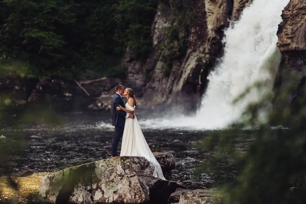 Kaitlyn and Evan kissing beside a waterfall during their mountain elopement