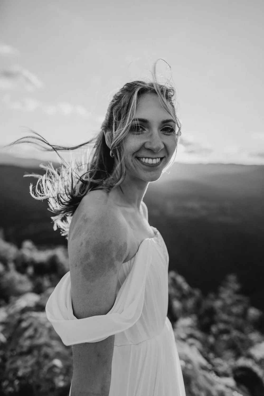 Black and white portrait of Kaitlyn smiling in the wind during sunset portraits in Linville Gorge