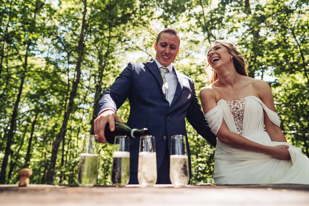 Kaitlyn and Evan laughing while pouring champagne after their small mountain elopement ceremony