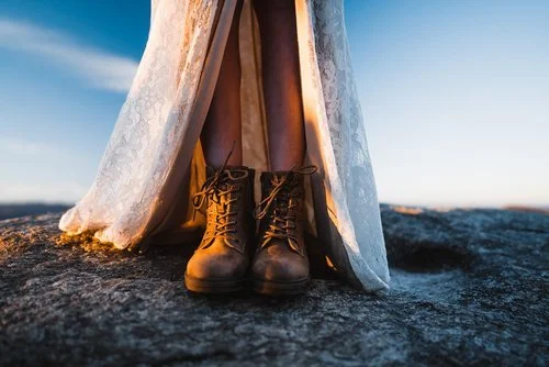 Bride wearing brown hiking boots with a lace wedding dress on rocky mountain terrain