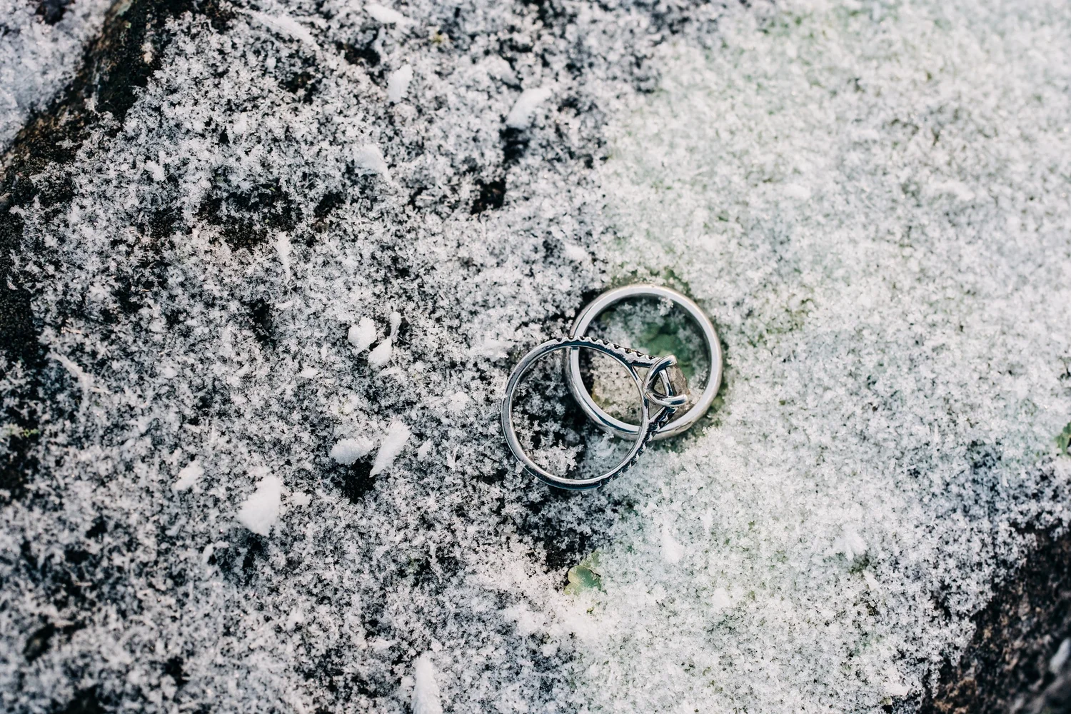 Two wedding rings resting in snow during a winter mountain elopement