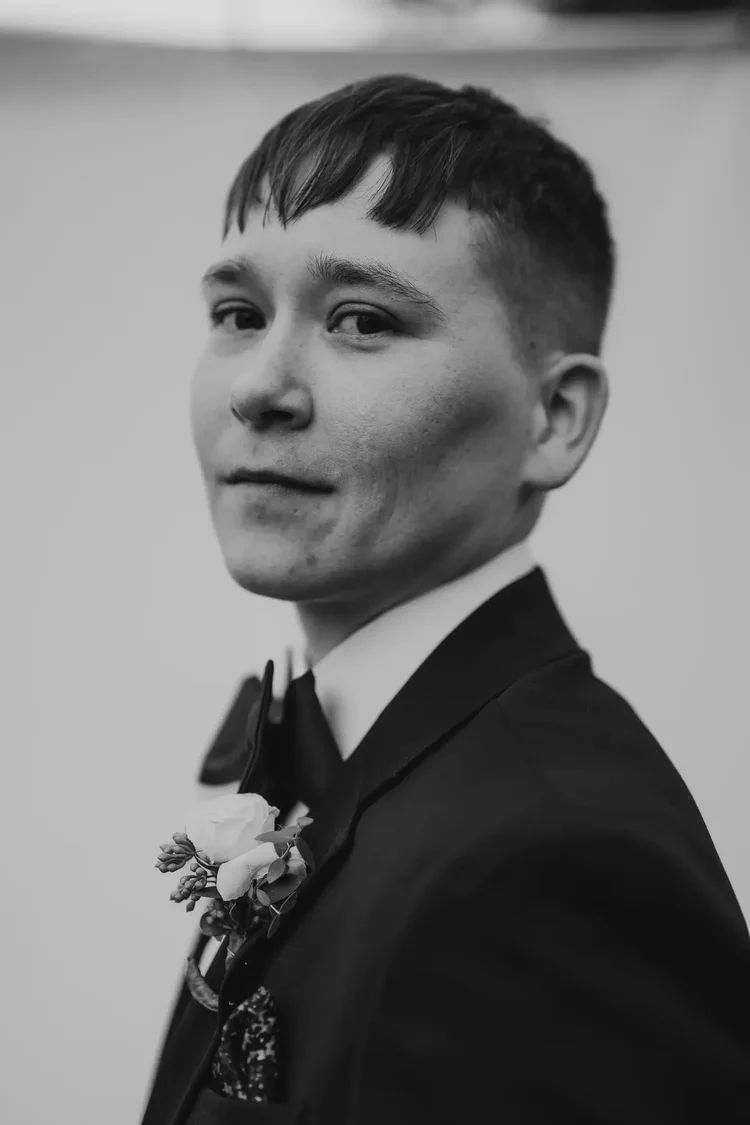 Black-and-white portrait of a groom wearing a tuxedo and boutonniere