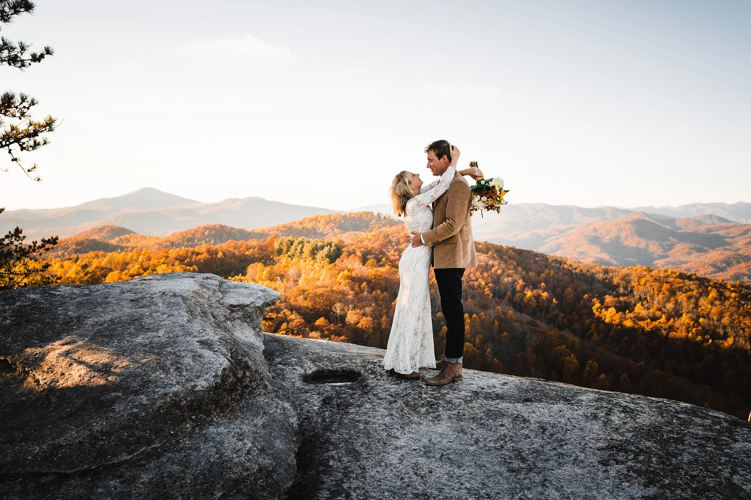 Mountain elopement couple embracing at an overlook surrounded by fall color