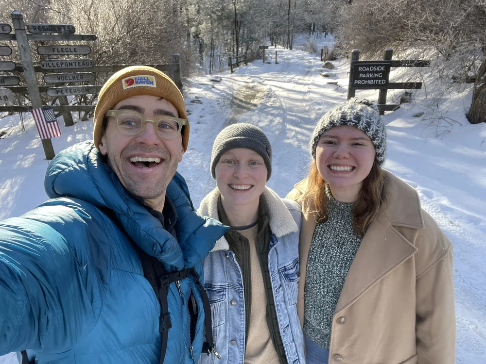 Photographer standing with a couple at a rocky mountain overlook