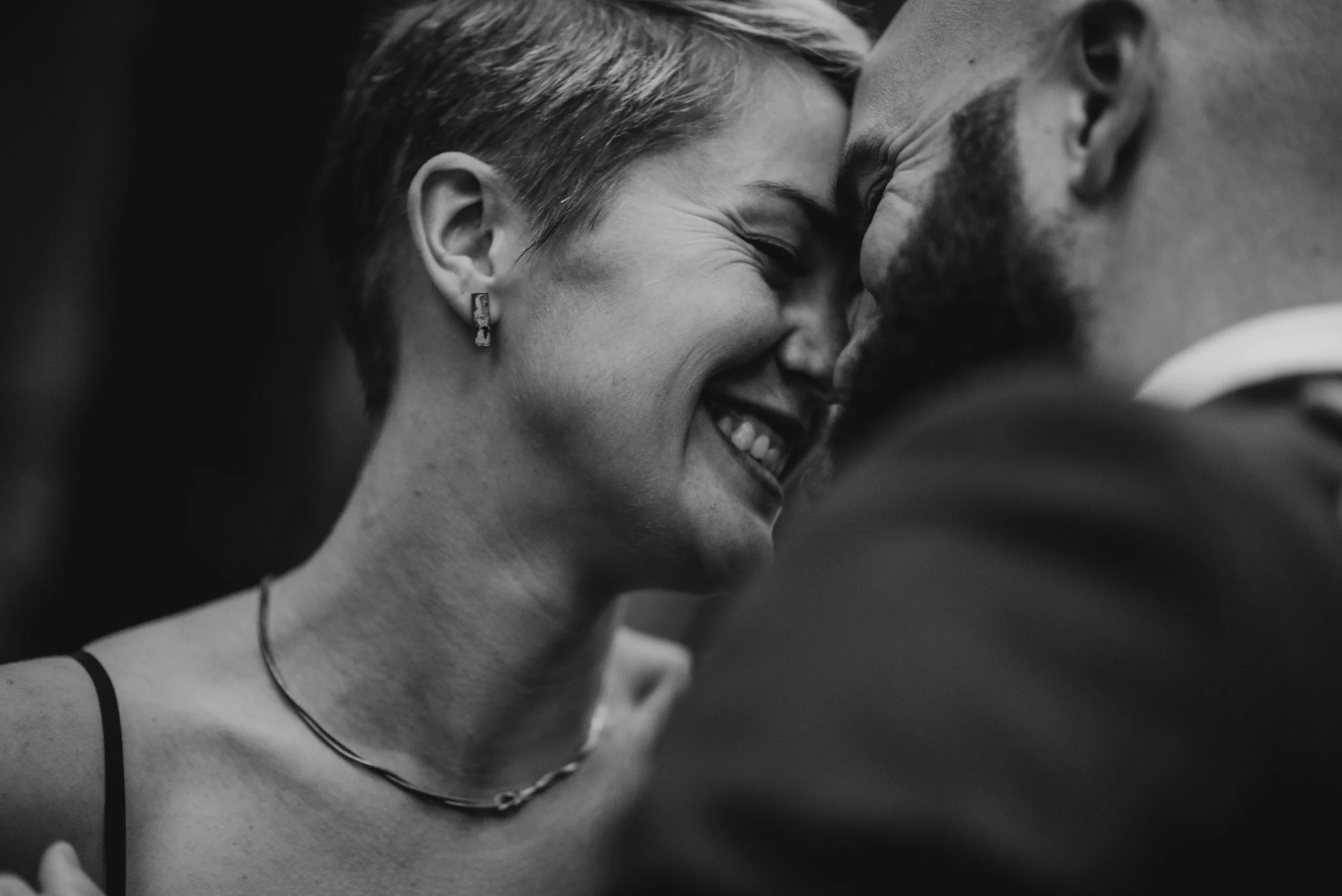 A woman smiles as she touches foreheads with her fiance.