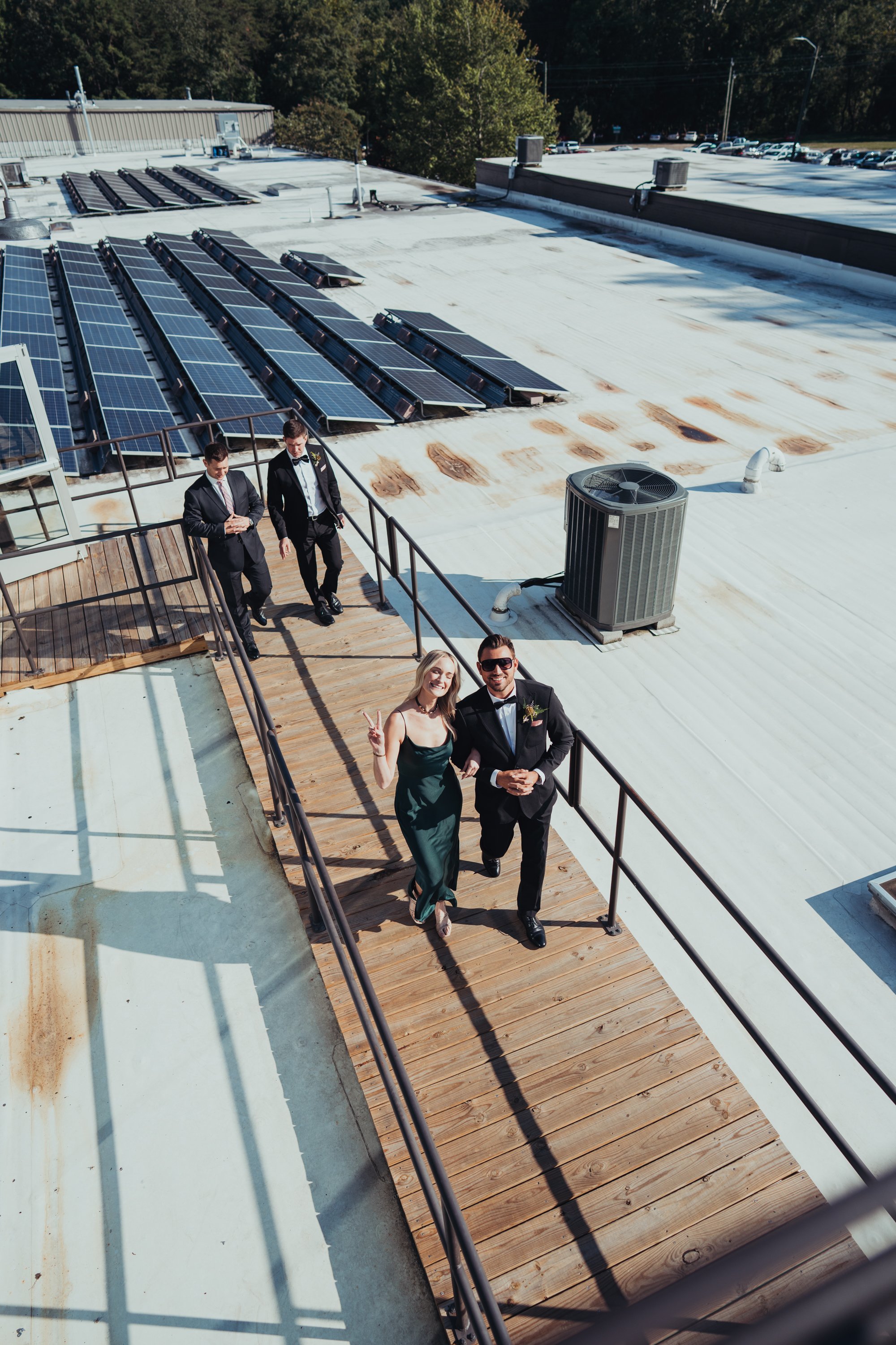 Group of people in formal attire on a rooftop with solar panels.