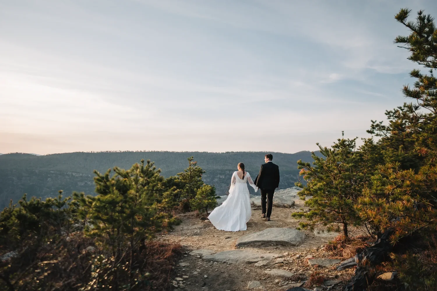 Newly married couple walking together along a rocky mountain trail