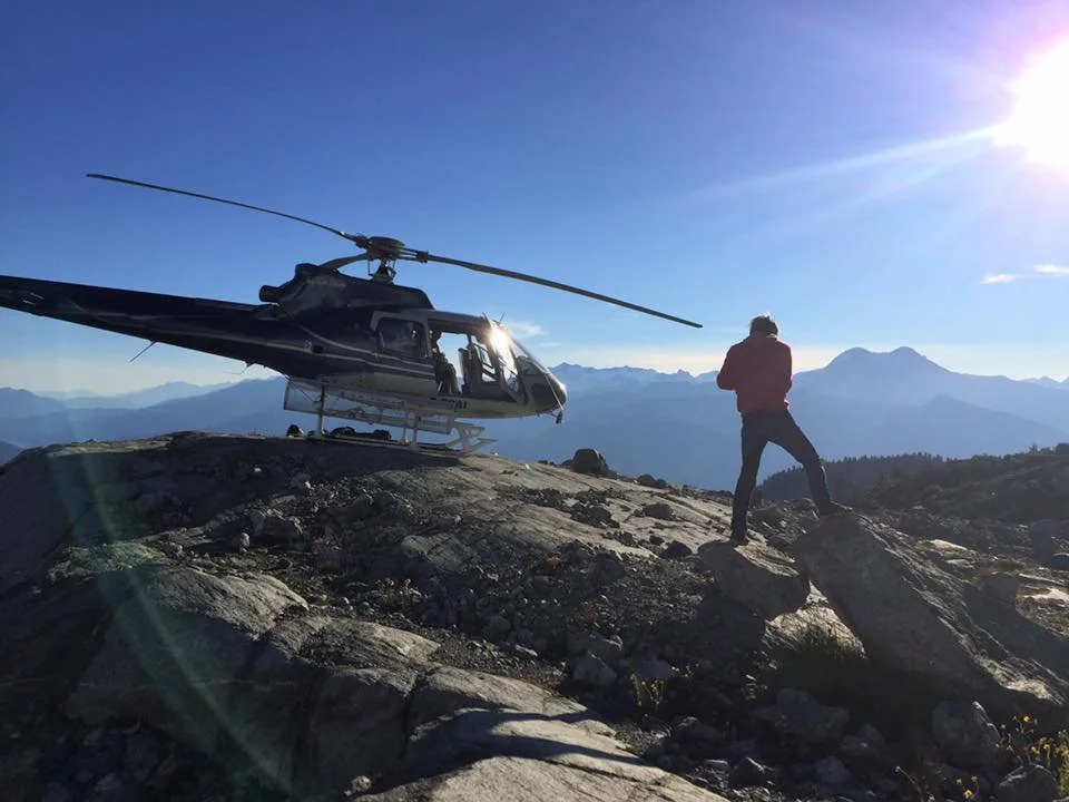 Helicopter and wedding group on a remote mountain glacier beneath a blue sky