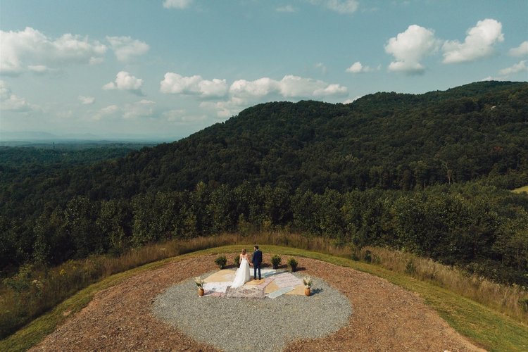 Aerial view of a couple surrounded by an expansive mountain landscape