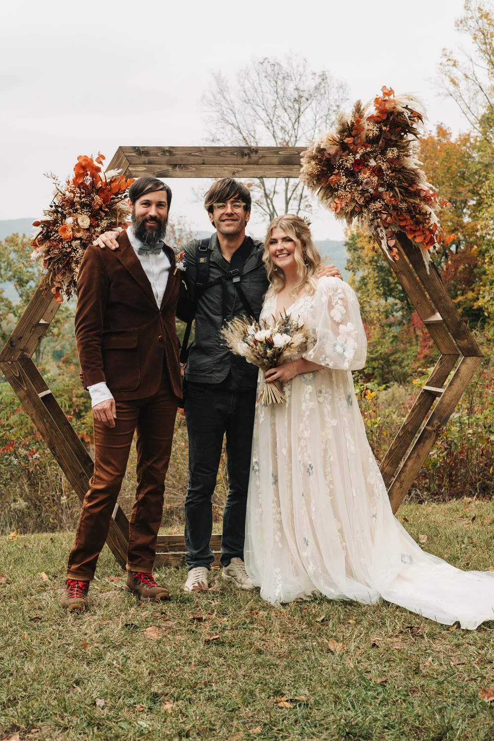 Photographer standing with a newly married couple after an outdoor autumn wedding