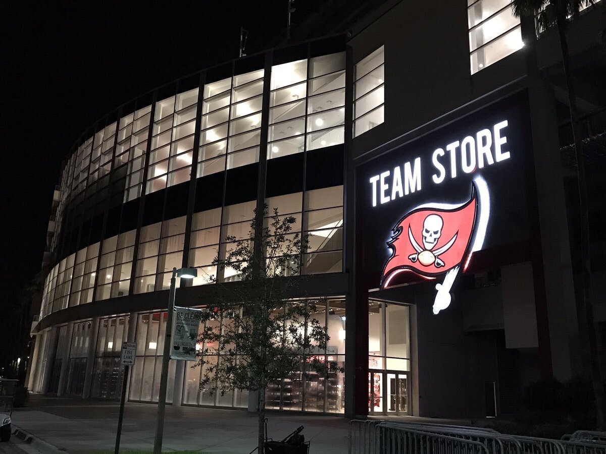 The team store logo is lit up at night on the exterior entrance of the Stadium. 