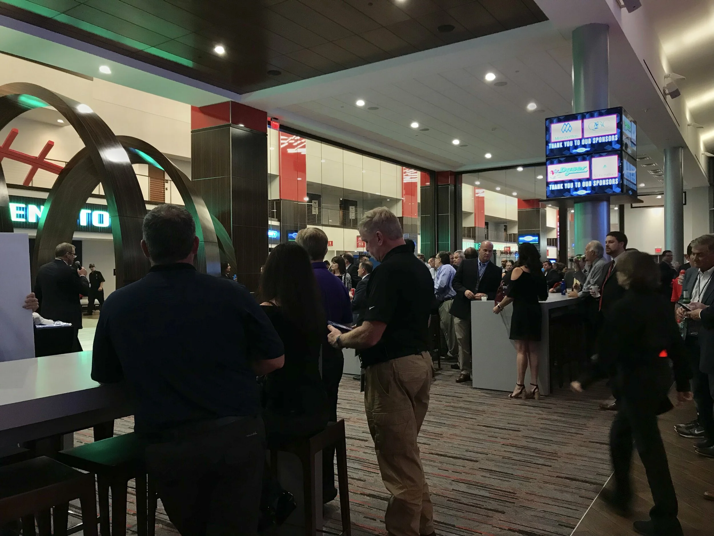 People stand at bar tables in the Hhyundai Club.