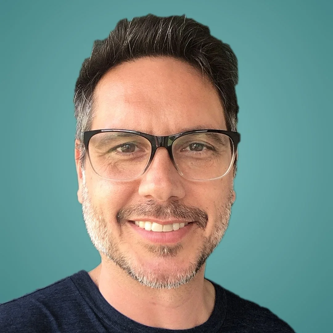 John DeMarco smiling, wearing glasses and a navy shirt