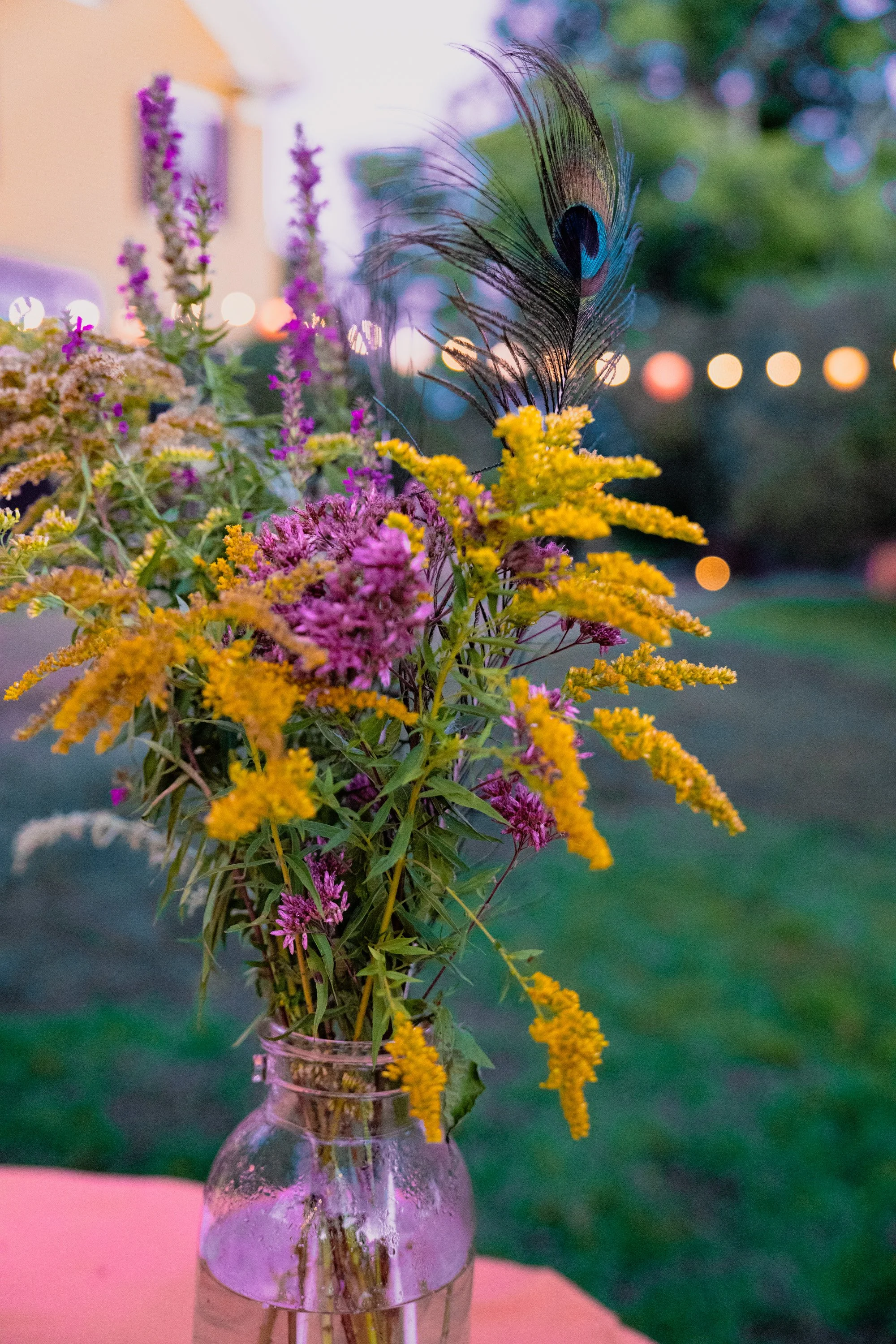 Vase of purple and yellow flowers with a blurry outside background.