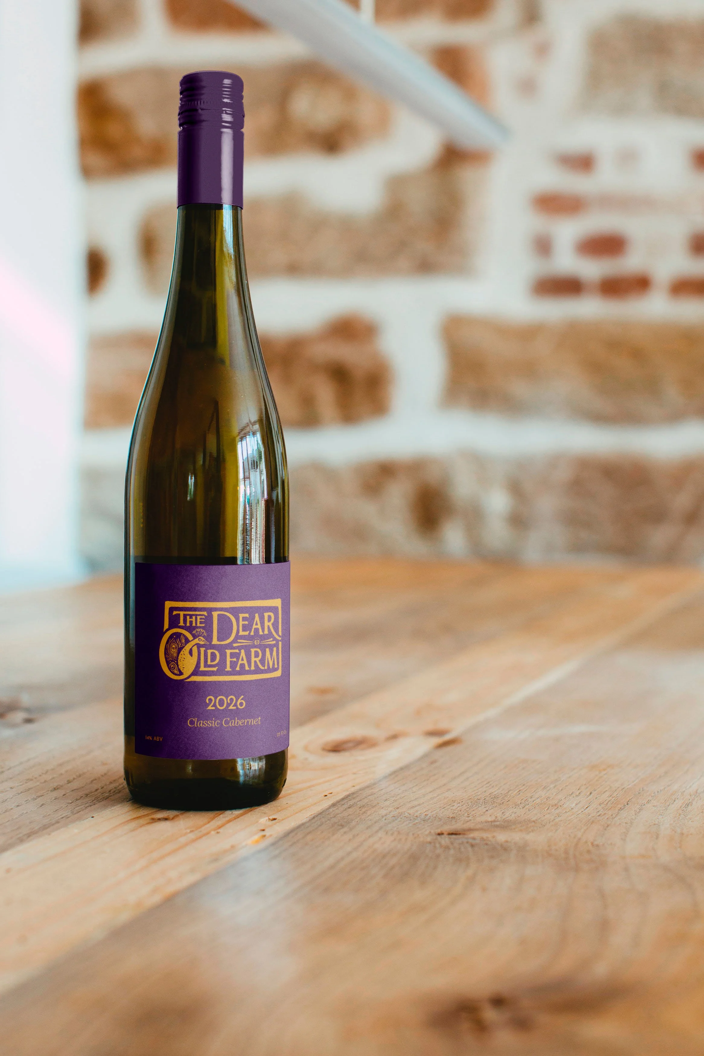 Wine bottle with purple label and Dear Old Farm logo in yellow.
