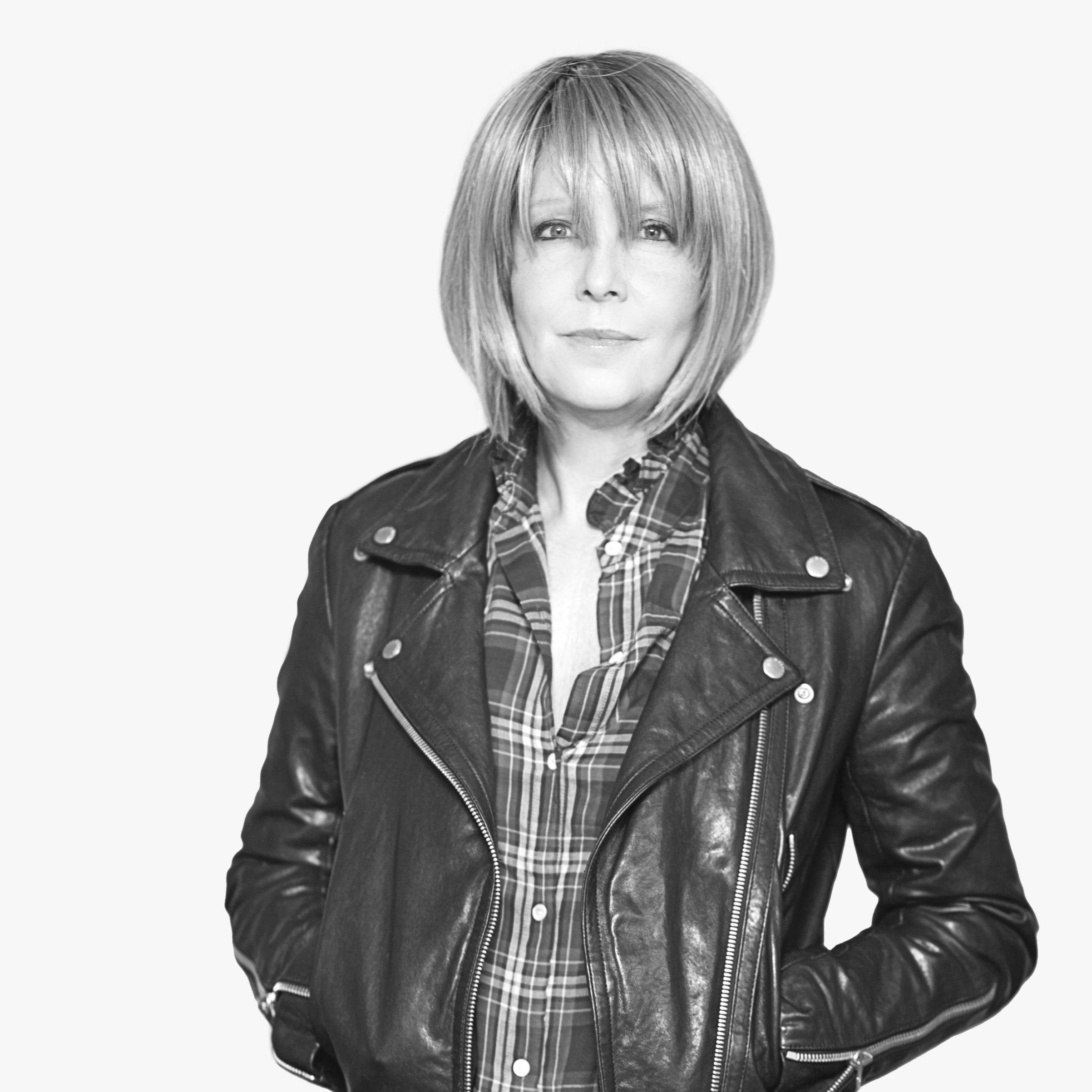 Black and white portrait of a woman with short blonde hair, wearing a leather jacket over a plaid shirt, posing with a confident expression.