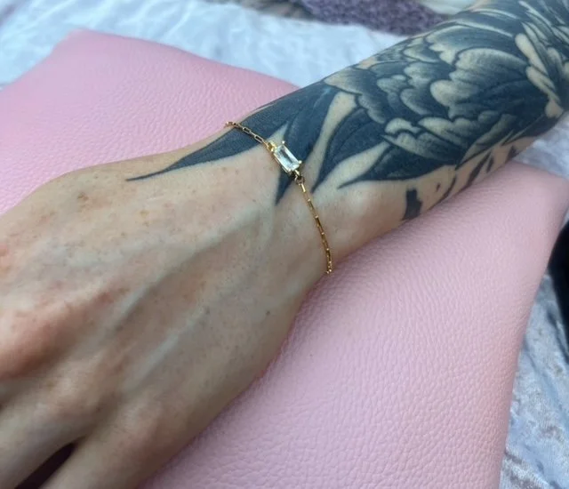 Tattooed forearm with a gold bracelet