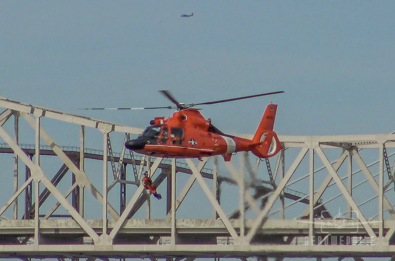 USCG Eurocopter MH-65 Dolphin lowering its pararescue swimmer on a line.