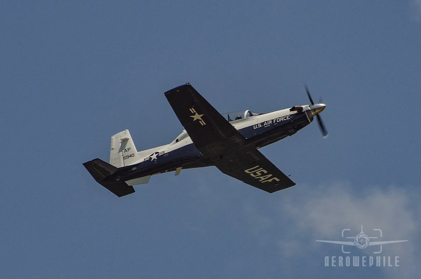 A U.S. Air Force Beechcraft T-6 Texan II passing overhead at the naval air station.