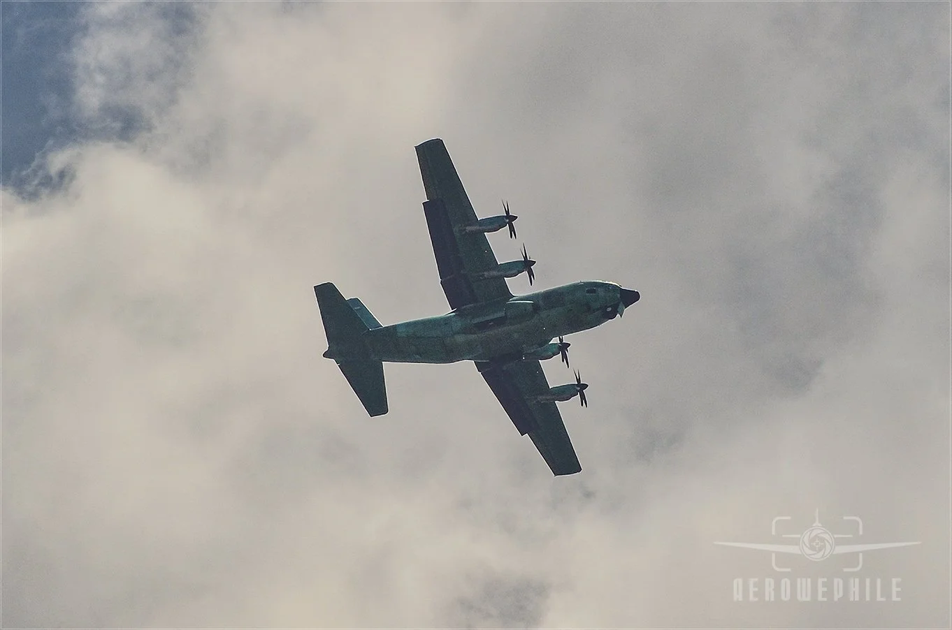 Unmarked and unpainted Lockheed C-130 Hercules passing low overhead PDK airport.
