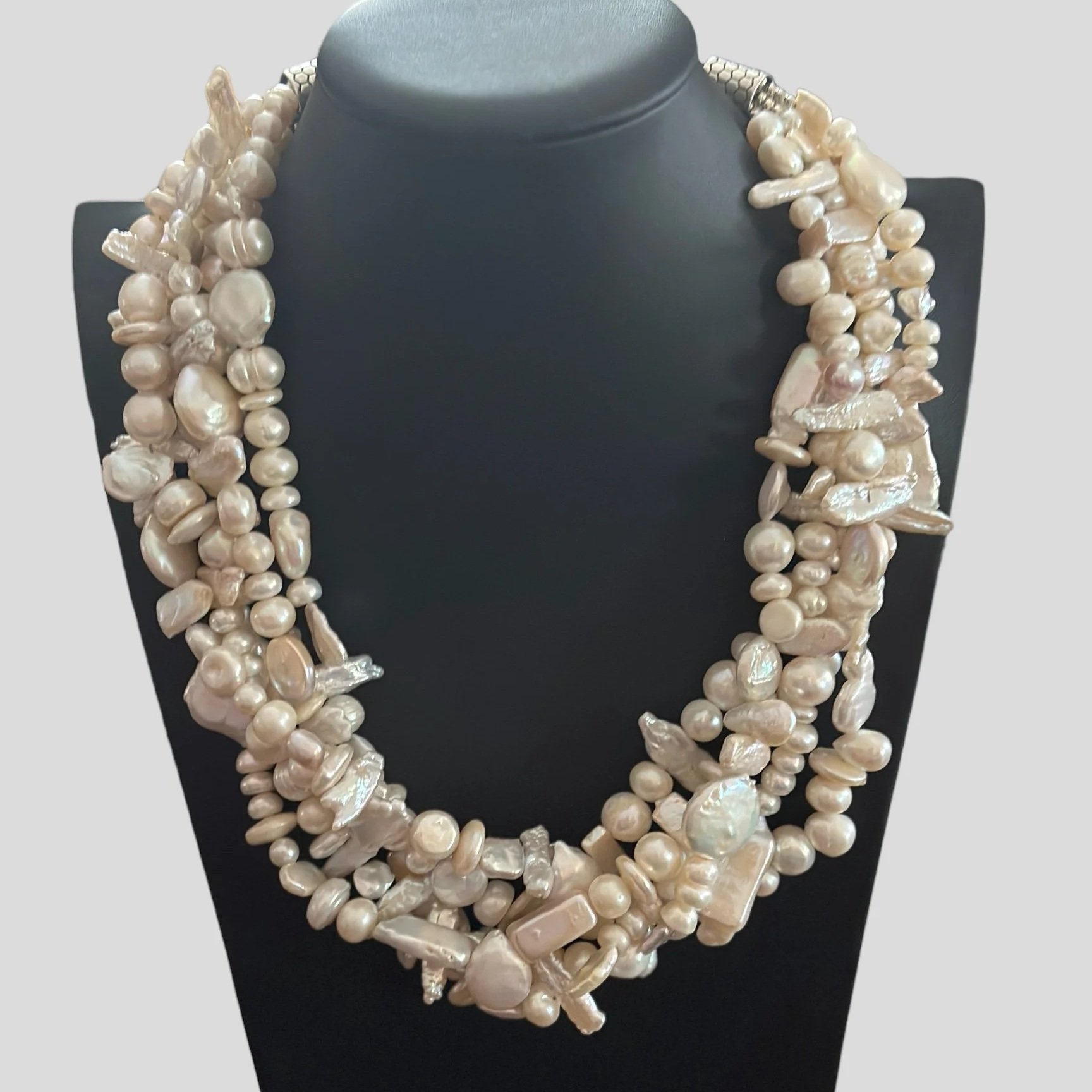 A black jewelry display bust showcasing a multi-strand pearl necklace with irregularly shaped pearls.