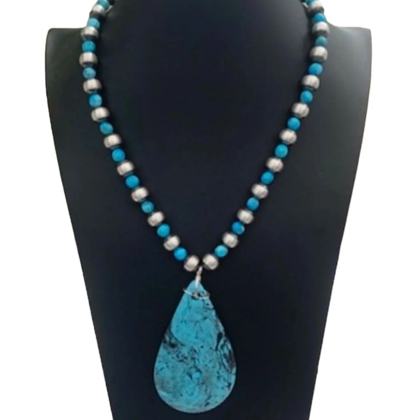 A beaded necklace with turquoise and silver beads, featuring a large teardrop-shaped turquoise pendant, displayed on a black mannequin bust. The text "Victoria's Southwest Designs" is written in blue at the bottom.