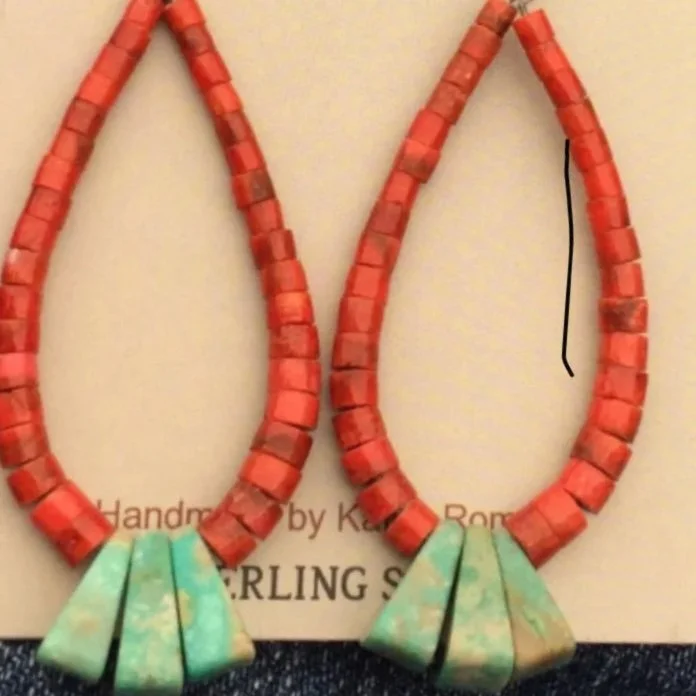 A pair of teardrop-shaped earrings with red beads forming the main loop and larger turquoise beads at the bottom, displayed on a jewelry card.