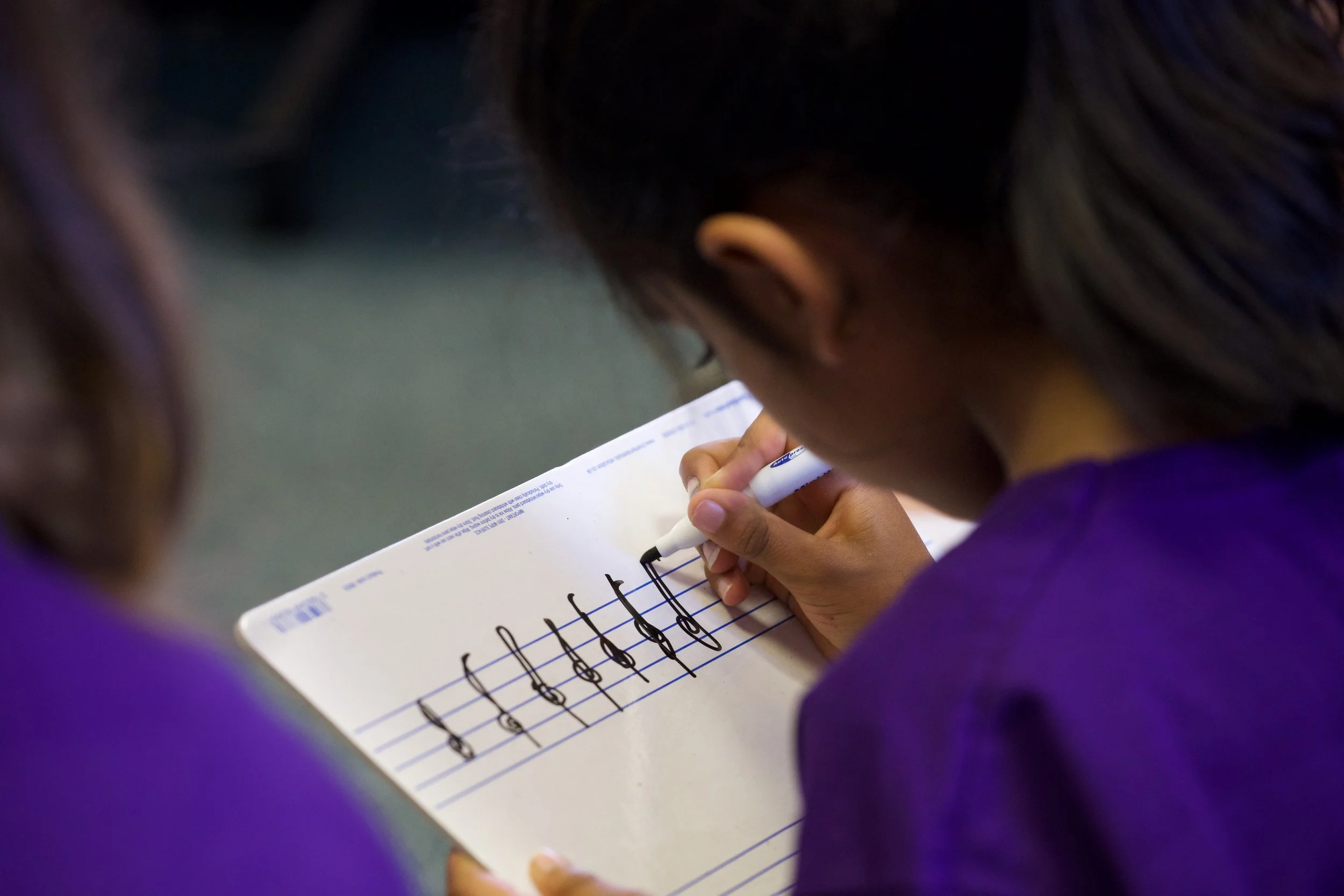 A child practises writing musical notes on a stave