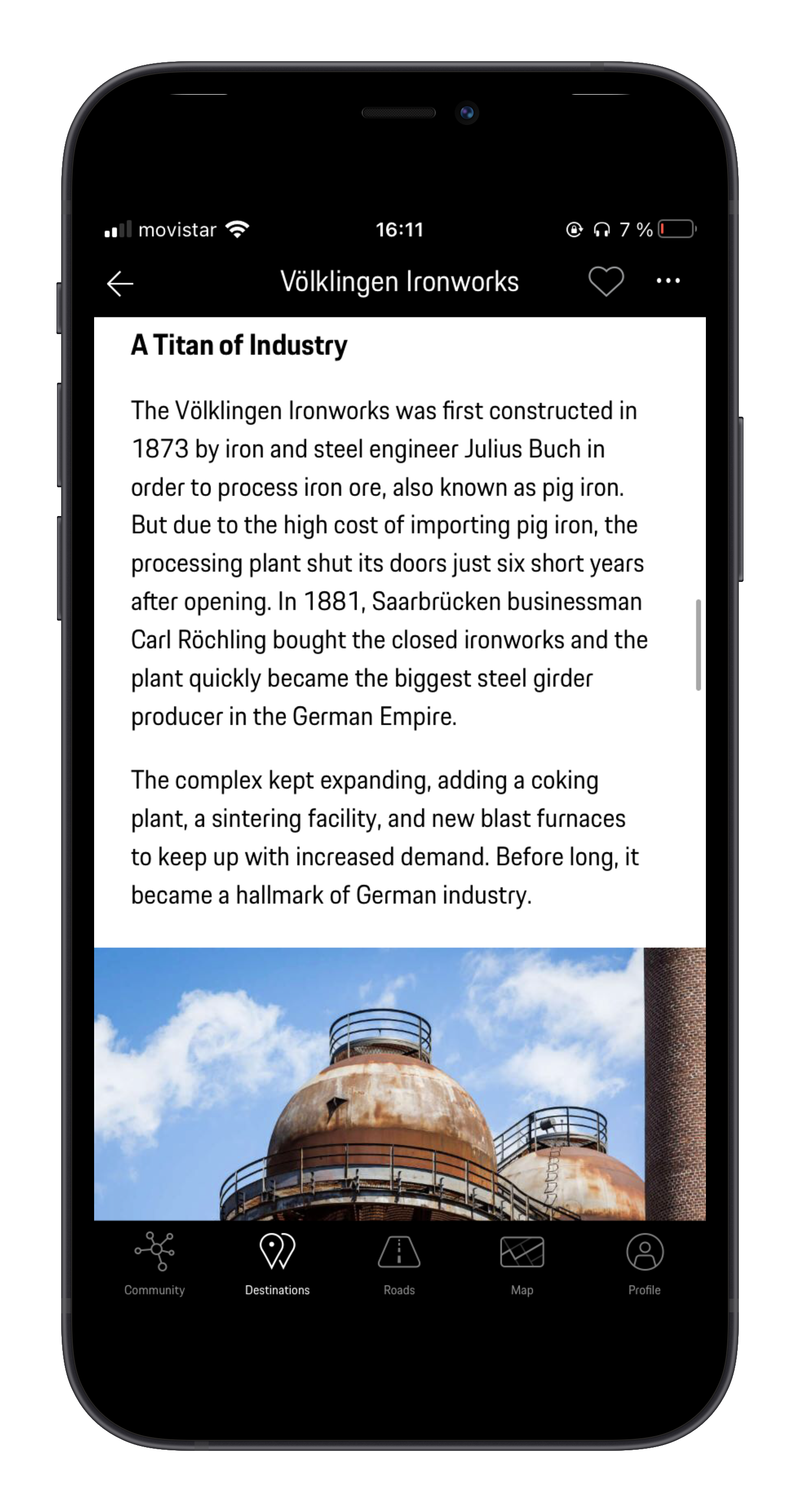 Smartphone screen displaying historical information about Völklingen Ironworks, with a photo of rusted industrial domes beneath a partly cloudy sky.
