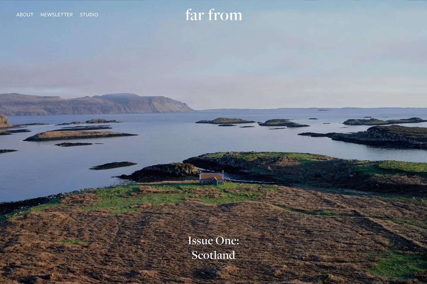 A scenic view of a Scottish coastal landscape featuring rocky islands, calm water, rolling green hills, and a small house near the shoreline with hills in the distance. Text overlay reads 'far from' and 'Issue One: Scotland'.