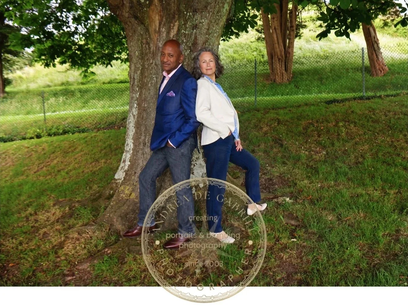 couple standing back to back under a tree and looking at the camera in powerful posing