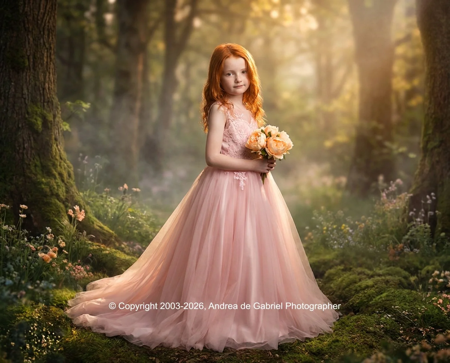 A young girl with red hair in a pink, flowy dress standing in a lush, green forest holding a bouquet of peach-colored flowers.
