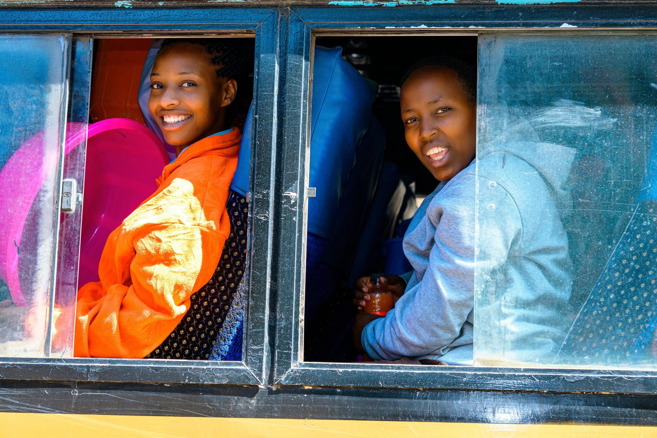 African girls going to school, on a school bus looking out the window.