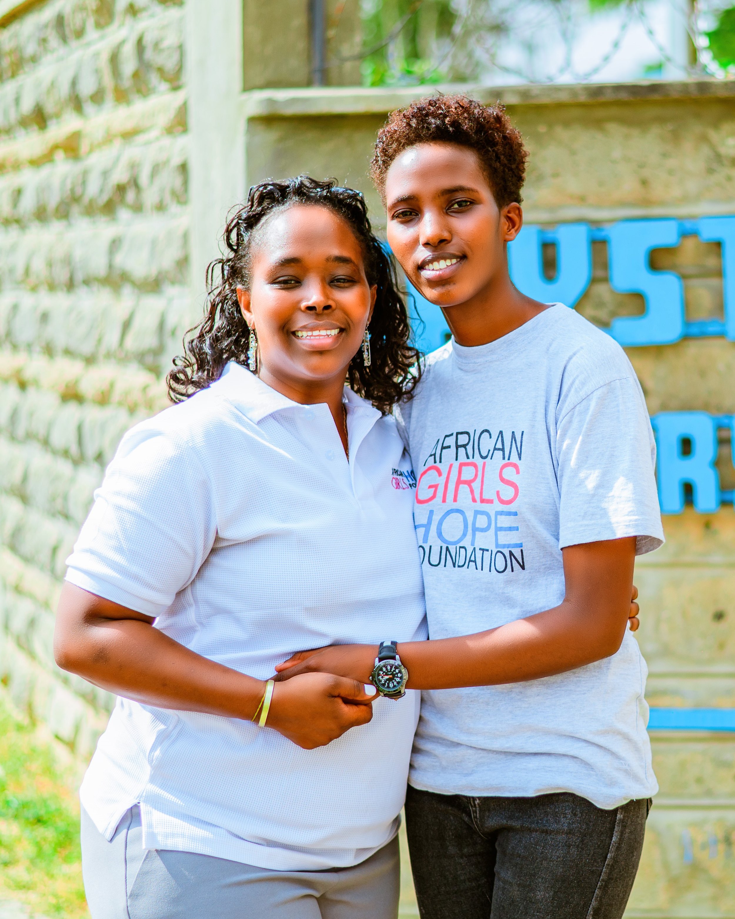 Dr. Grace with scholarship recipient Beatrice in front of her university.