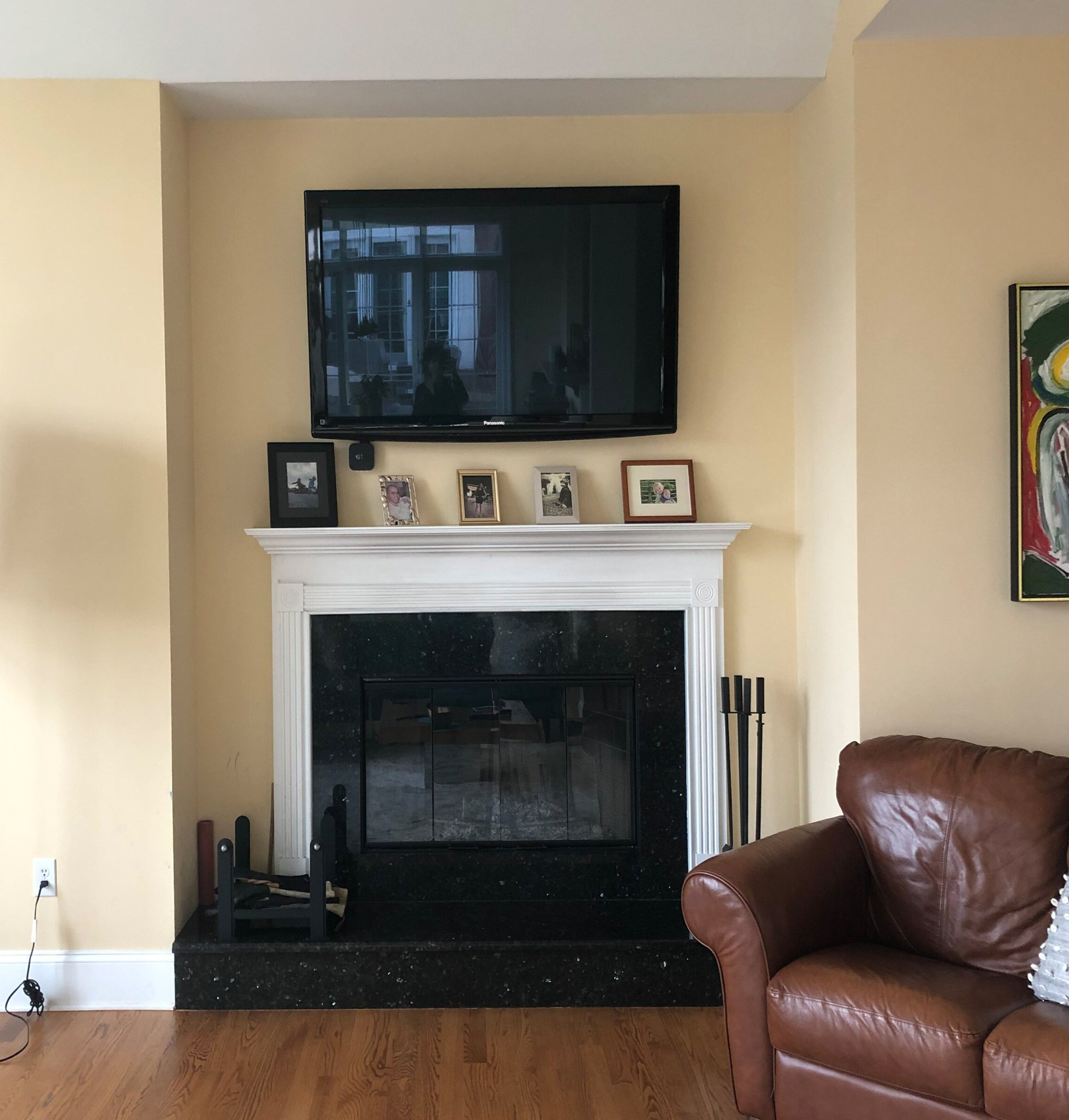  old fireplace, wood mantle, black stone hearth,  brown leather loveseat 