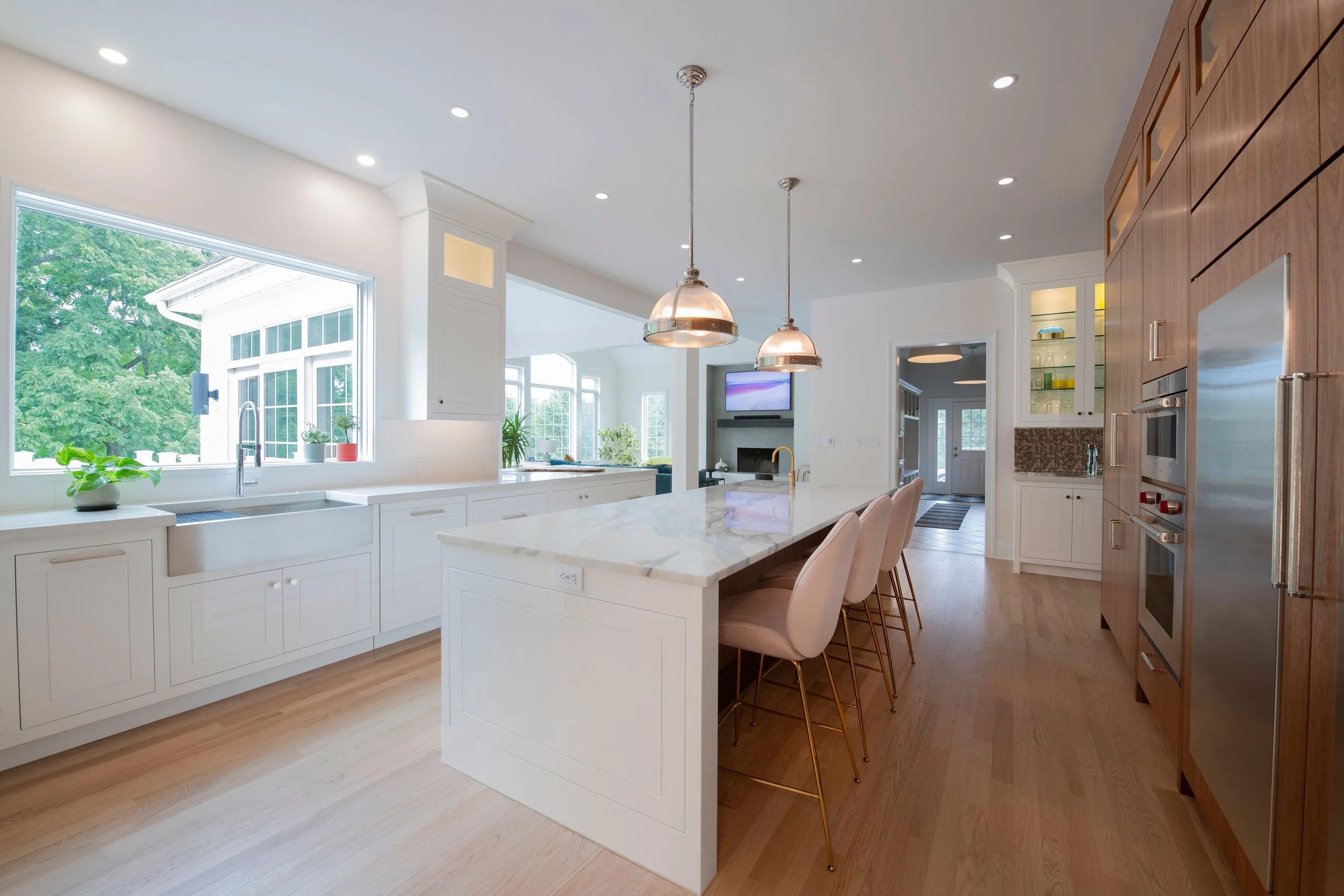 contemporary and bright kitchen with custom white and wood cabinets, white island, natural stone countertops, pendants, light boxes, gold zip drain, wolf range, double oven, coffee compartment, hidden microwave,  hardwood floors,  Interior design, in