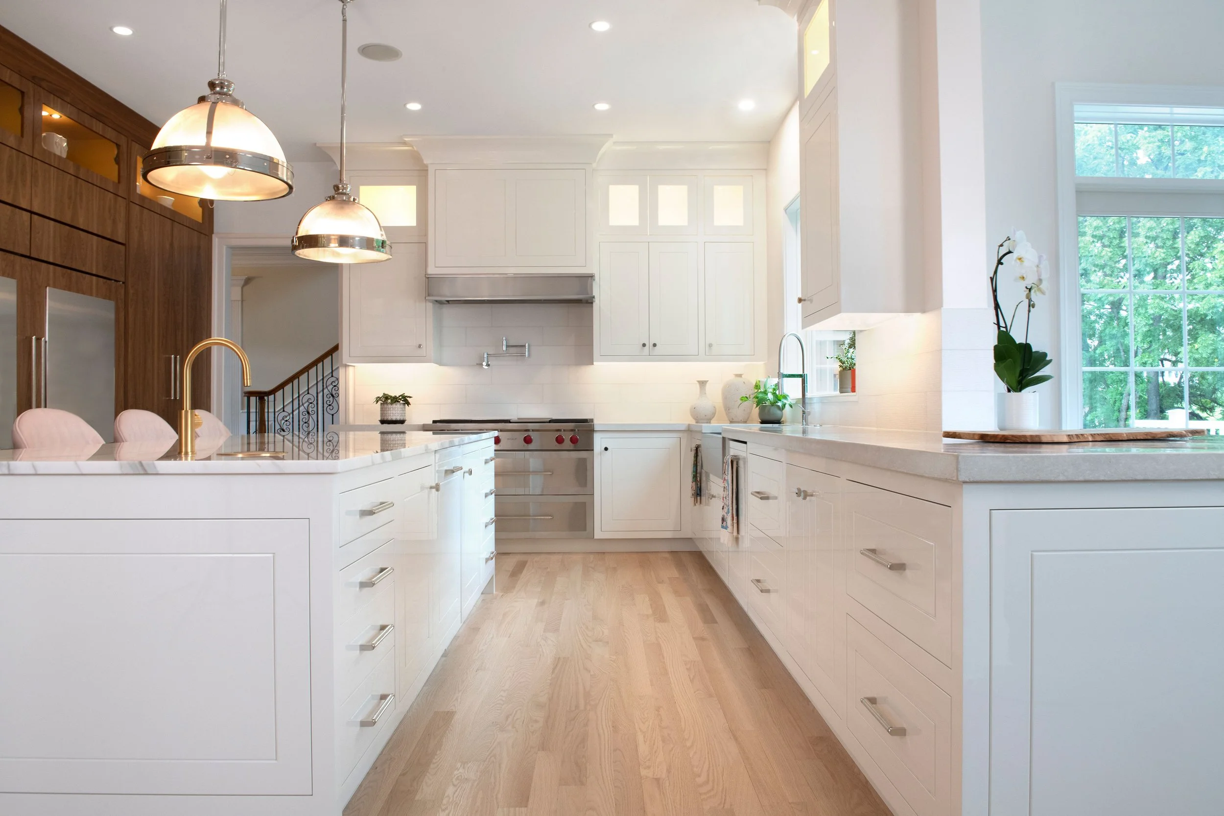 contemporary and bright kitchen with custom white and wood cabinets, white island, natural stone countertops, pendants, light boxes, gold zip drain, wolf range, double oven, coffee compartment, hidden microwave,  hardwood floors,  Interior design, in