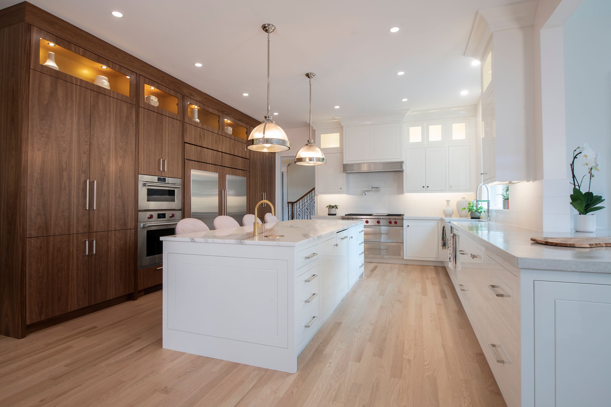 contemporary and bright kitchen with custom white and wood cabinets, white island, natural stone countertops, pendants, light boxes, gold zip drain, wolf range, double oven, coffee compartment, hidden microwave,  hardwood floors,  Interior design, in