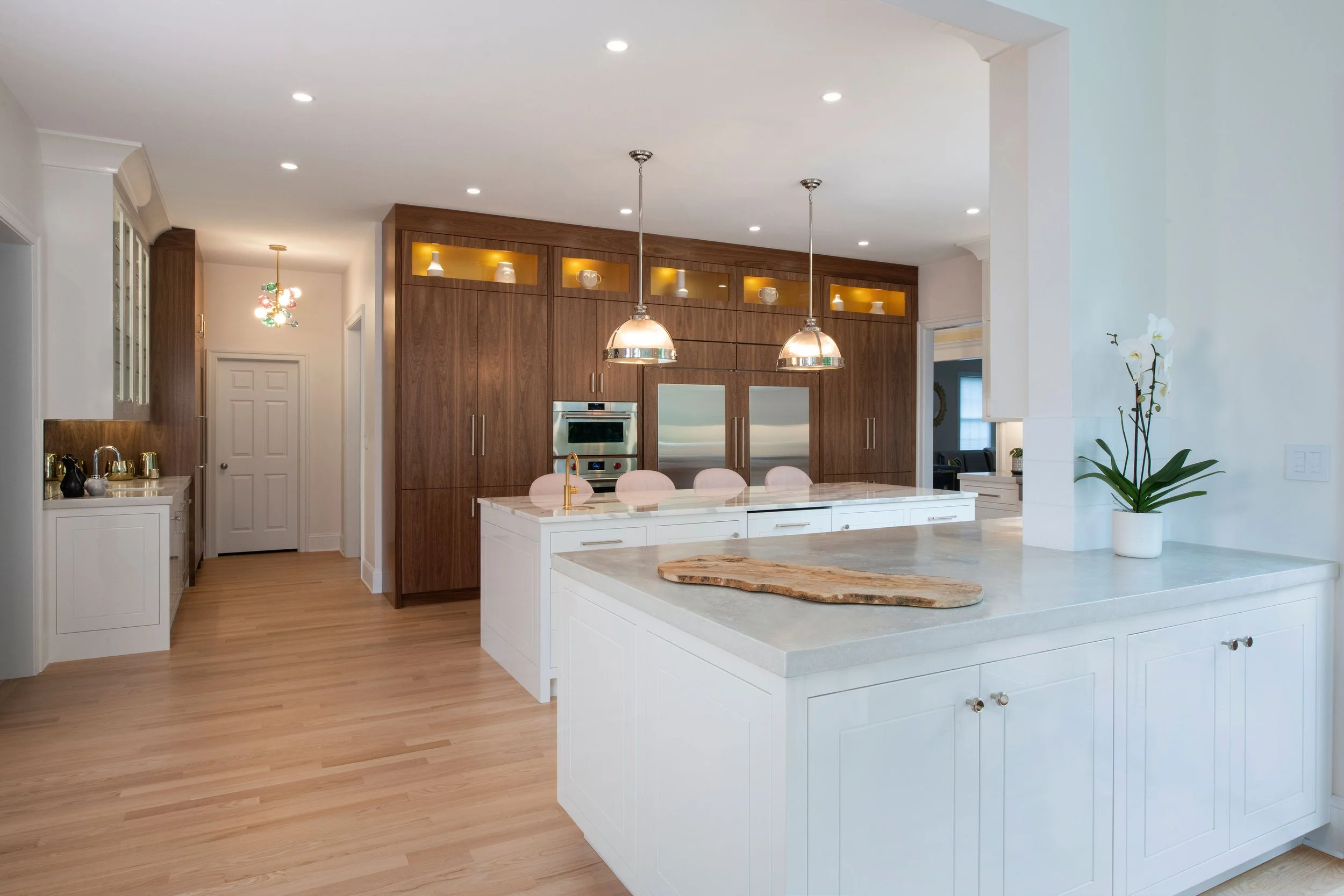 contemporary and bright kitchen with custom white and wood cabinets, white island, natural stone countertops, pendants, light boxes, gold zip drain, wolf range, double oven, coffee compartment, hidden microwave,  hardwood floors,  Interior design, in
