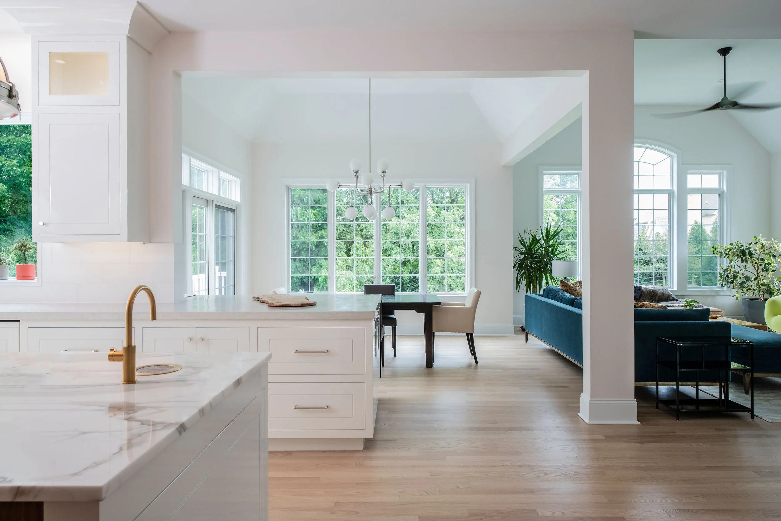 contemporary and bright kitchen with custom white and wood cabinets, white island, natural stone countertops, pendants, light boxes, gold zip drain, wolf range, double oven, coffee compartment, hidden microwave,  hardwood floors,  Interior design, in