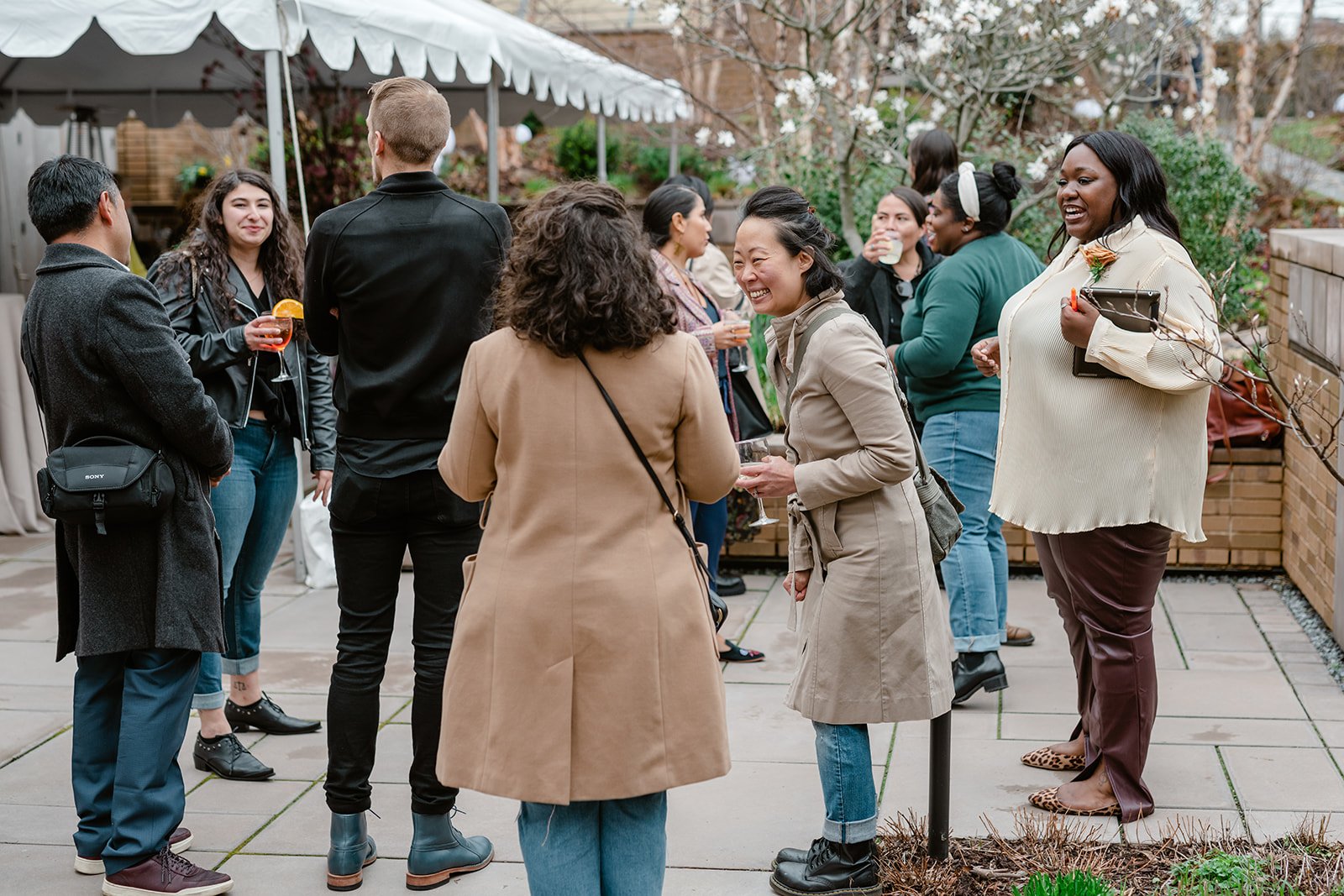  Party guests laughing in outdoor, tented courtyard at Carroll Hall event venue in Brooklyn, NY  