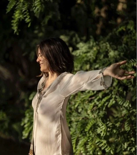 A happy woman with open arms in a forest