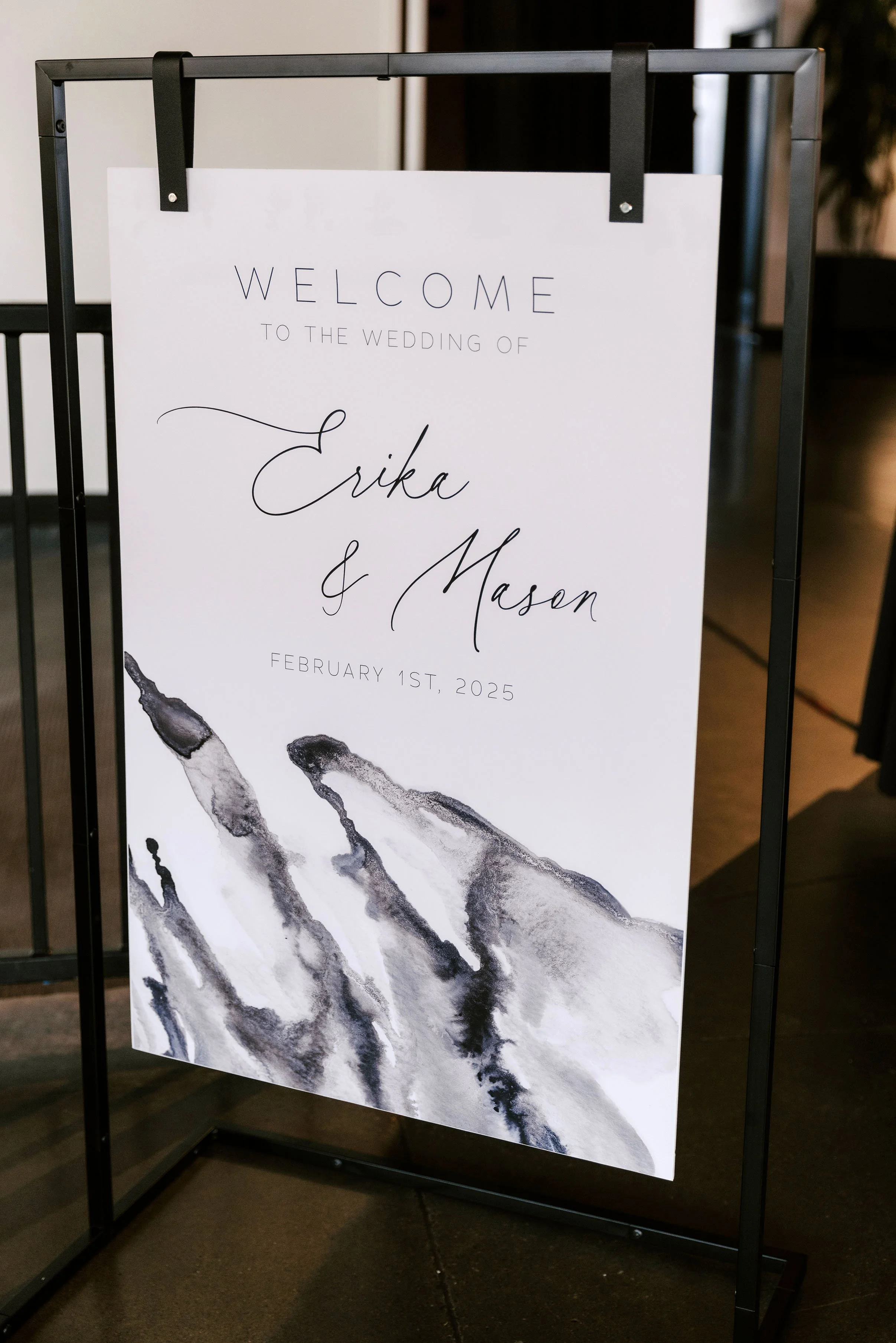 Custom wedding welcome sign with black frame and white background, featuring black and white marbled watercolor at the bottom, and elegant black script text that says 'Welcome to the wedding of Erika & Mason, February 1st, 2025.'