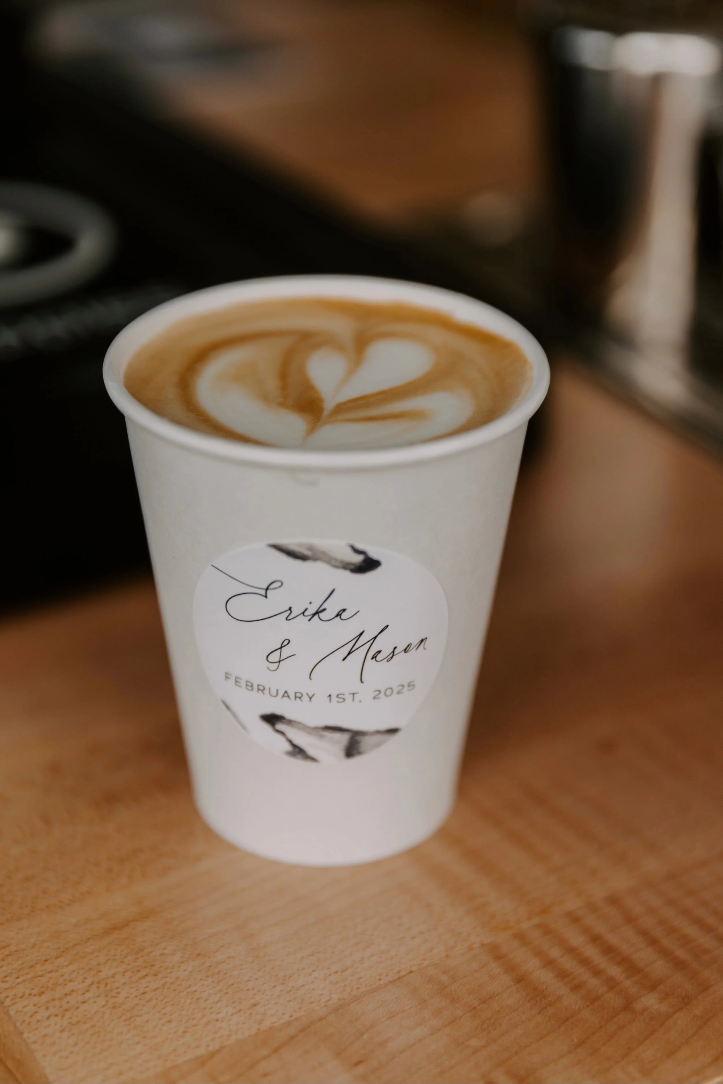 Coffee drink at wedding with custom art sticker on cup with couple's name in calligraphy and black and white marbled watercolor design