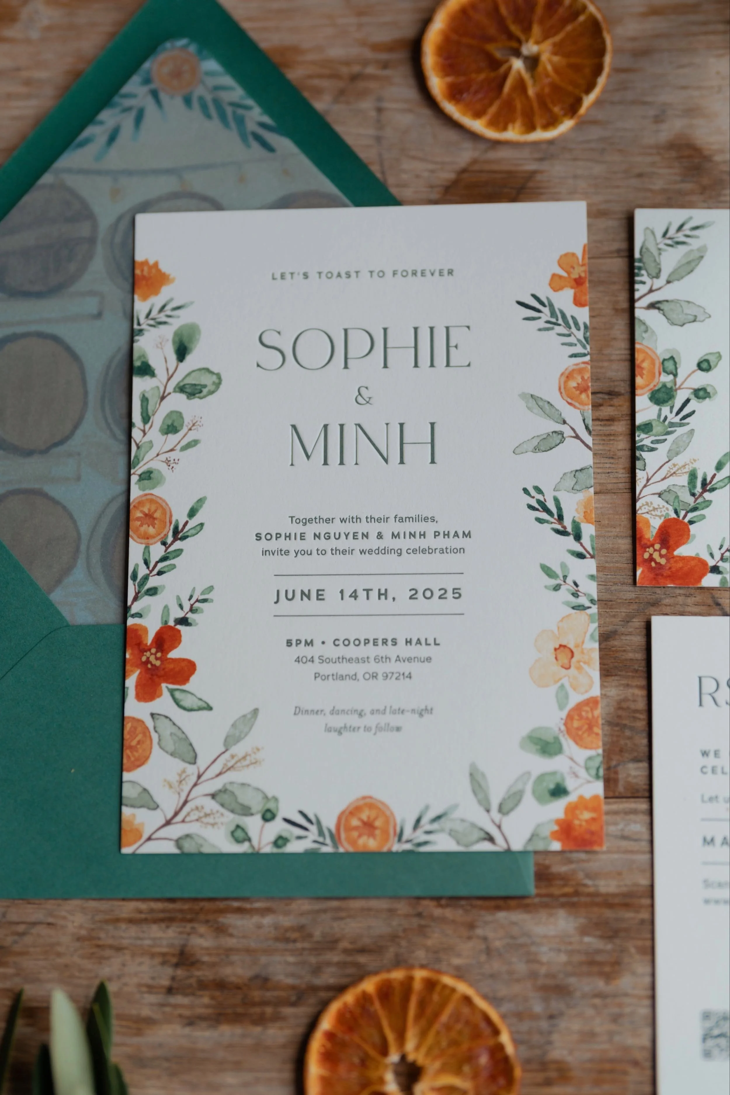 Wedding invitation suite flat lay with custom watercolor art of citrus slices and orange flowers, with letterpressed typography at the Coopers Hall wedding venue in Portland, Oregon