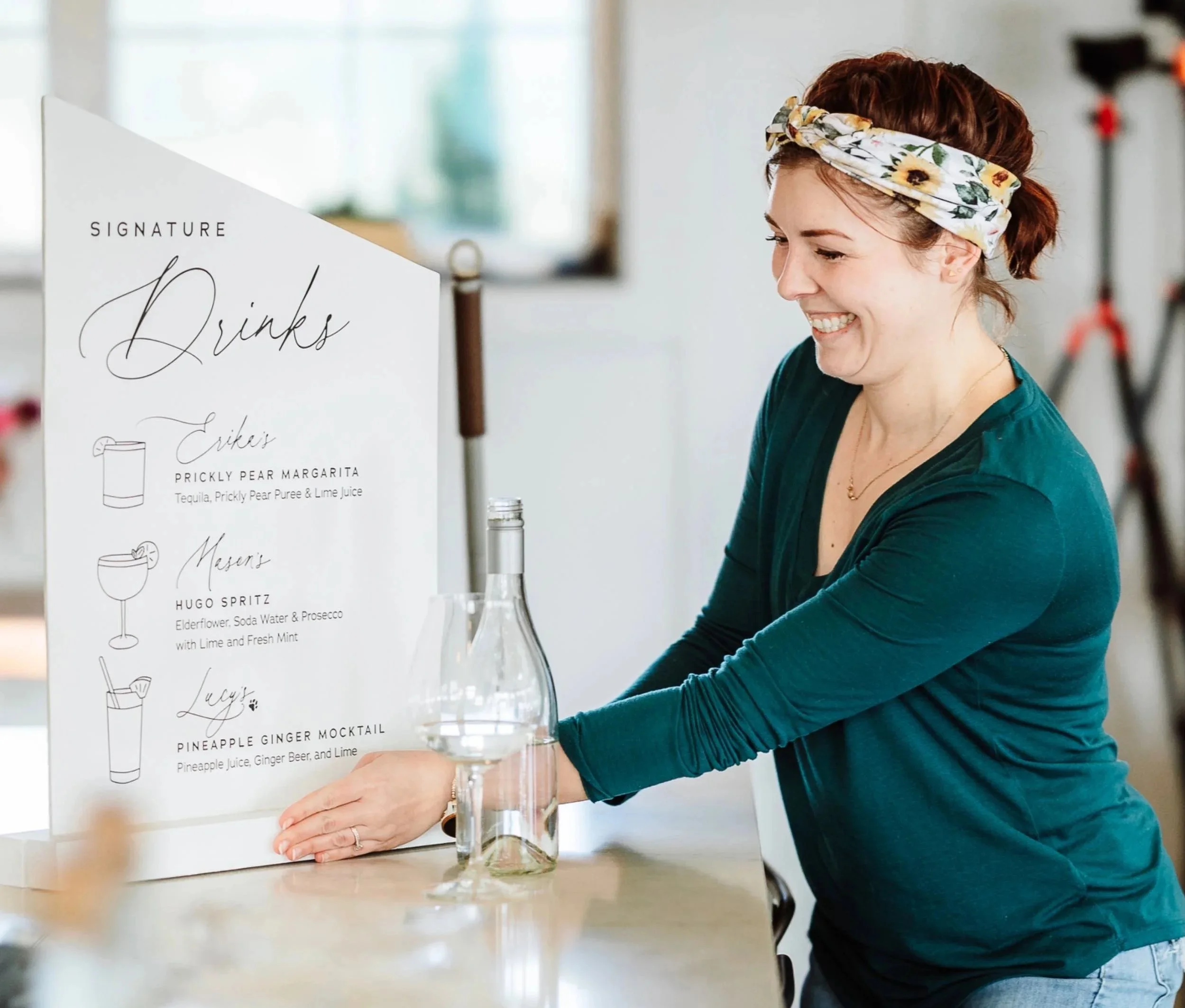 Michelle Roberts setting up a custom bar sign for wedding with signature drink illustration and elegant cursive typography