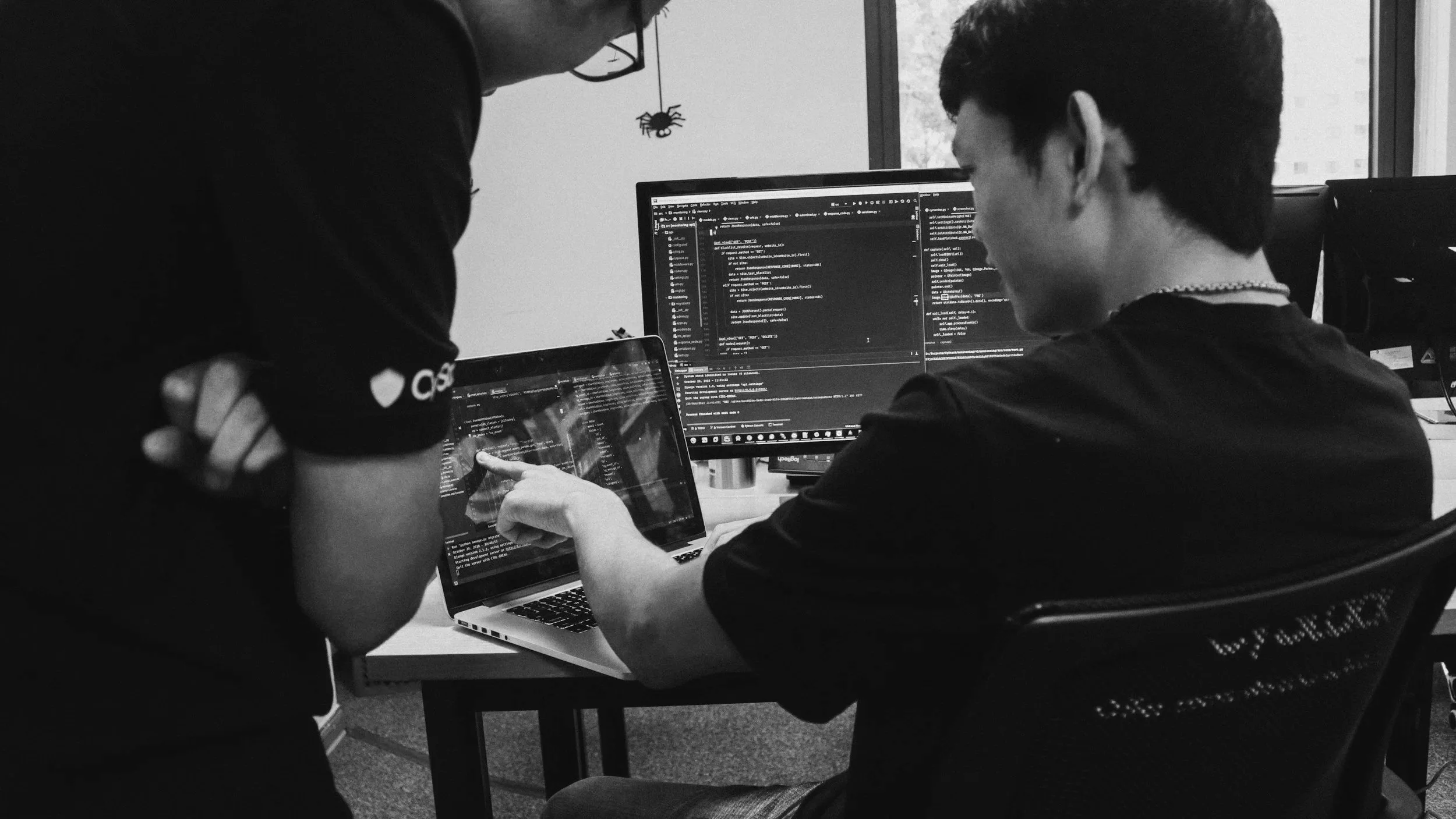 Man pointing at lines of code on a screen while a CISA agent watches