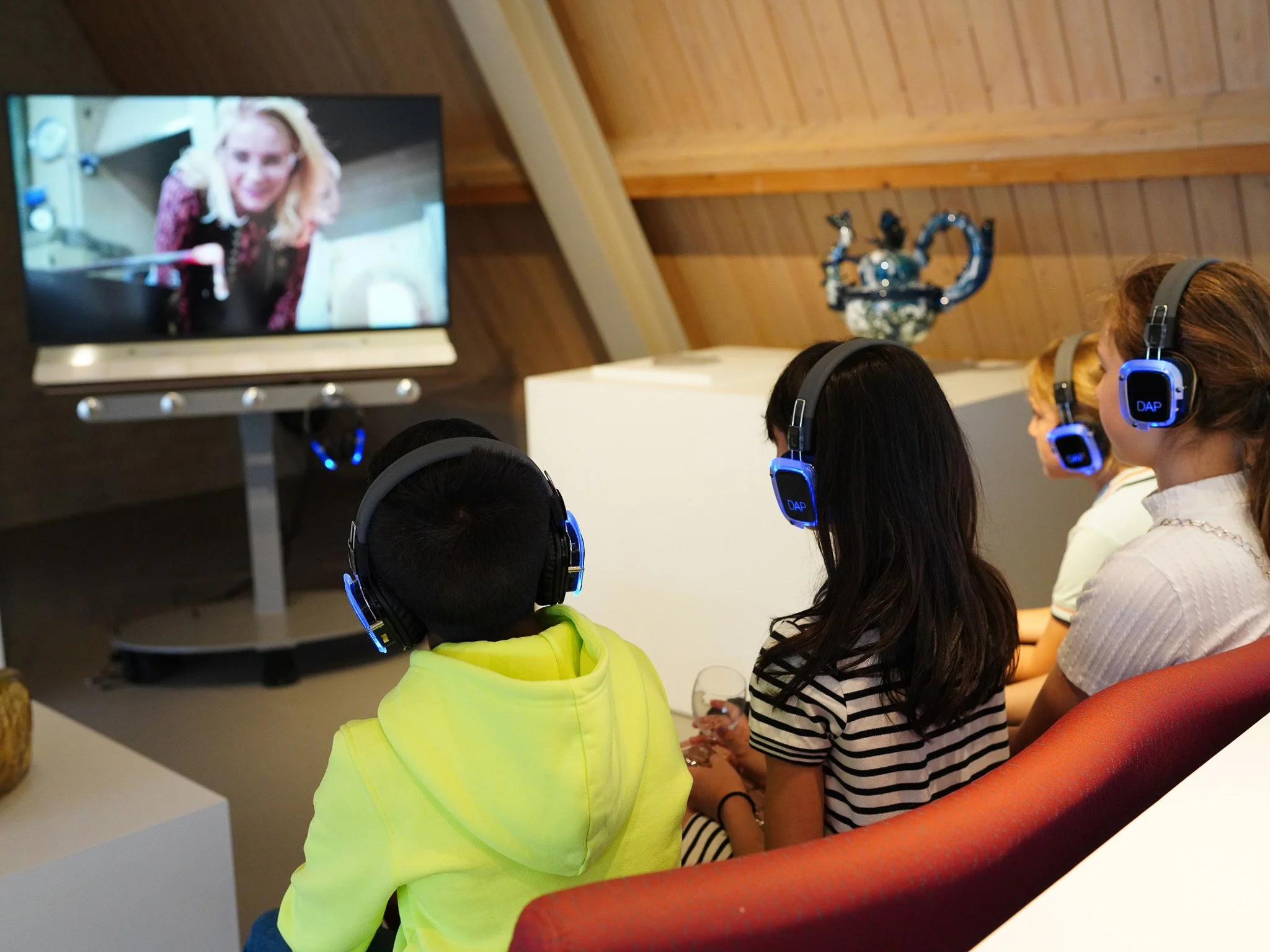 Vier kinderen kijken naar een video waarin glaskunst gemaakt wordt